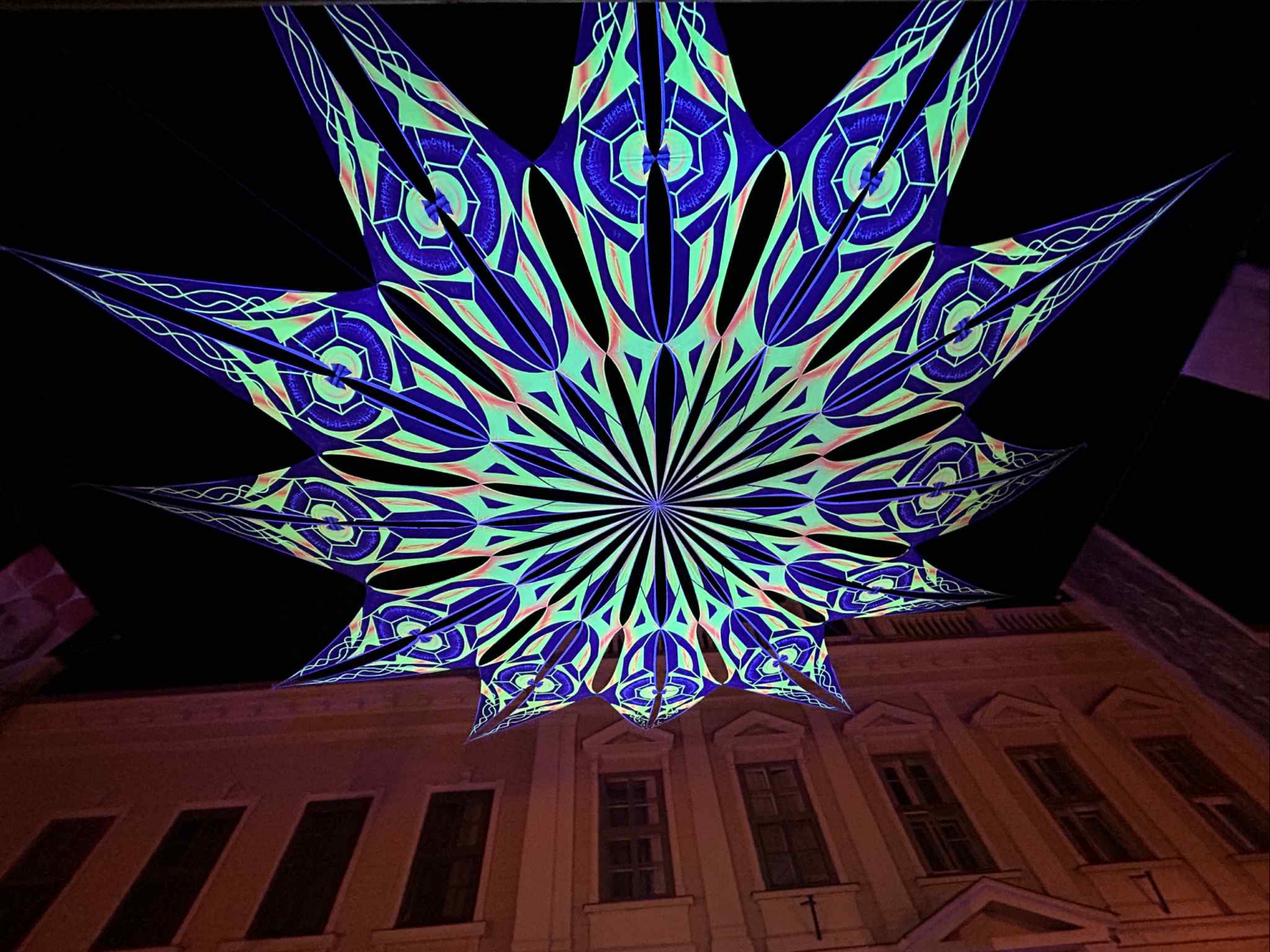 UV-aktív dekorponyva közeli nézete esti megvilágításban, geometrikus mintázattal.